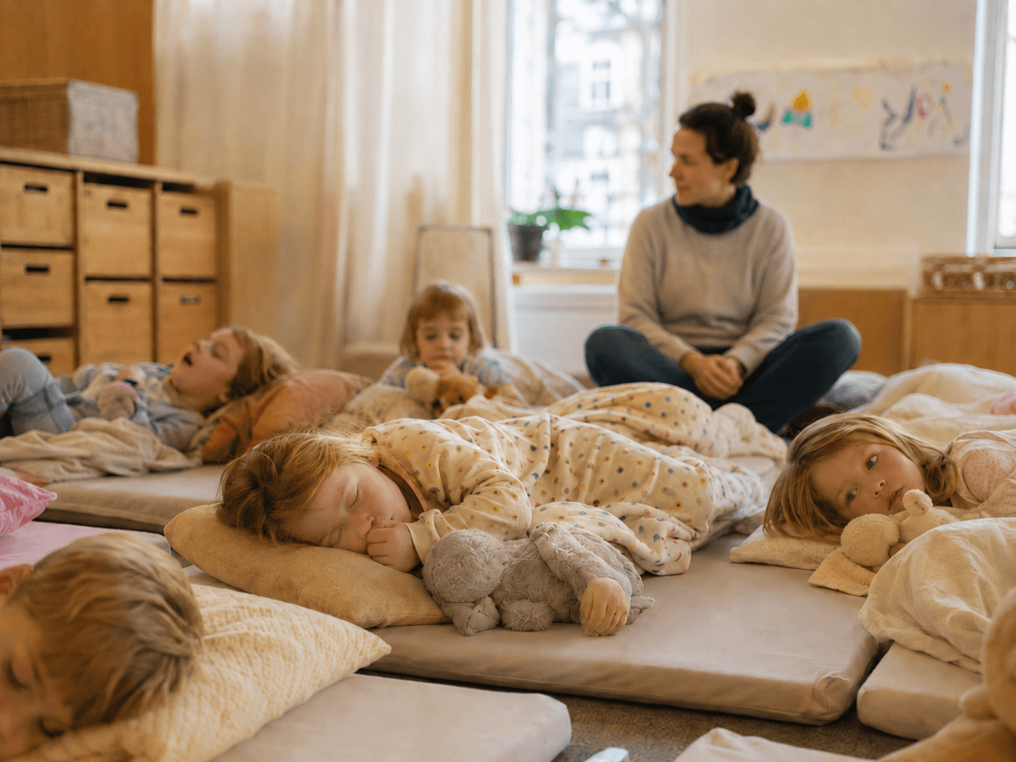 Kinder schlafen bei der Ruhezeit im Kindergarten auf Matten